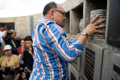 Randy delos Santos meletakkan guci berisi abu korban di Manila, Filipina, Rabu (12/3/2025). Foto: JAM STA ROSA / AFP