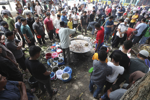 Warga antre mengambil menu kuliner tradisional kuah beulangong daging sapi pada perayaan kenduri Nuzulul Quran di Desa Doy Ulee Kareng, Banda Aceh, Aceh, Senin (17/3/2025). Foto: Irwansyah Putra/ANTARA FOTO