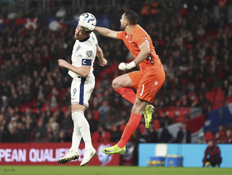 Pemain Timnas Inggris Harry Kane berebut bola dengan penjaga gawang Albania Thomas Strakosha pada pertandingan leg pertama perempat final di Stadion Wembley, London, Inggris, Jumat (21/3/2025). Foto: David Klein/Reuters