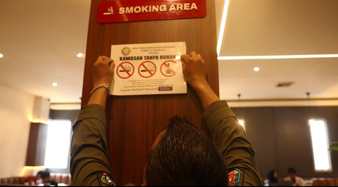 Petugas Pol PP Kota Pontianak saat menempelkan peringatan 'Kawasan Tanpa Rokok' di sebuah coffee shop di Pontianak. Foto; Dok. Istimewa