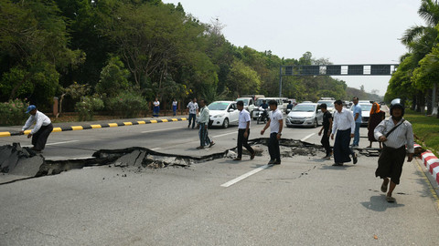 Warga memunguti serpihan jalan yang rusak di Naypyidaw pada 28 Maret 2025, setelah gempa bumi di Myanmar bagian tengah. Foto: Sai Aung MAIN / AFP