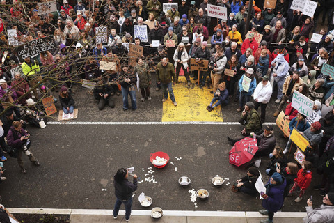 Orang-orang melambaikan tangan dan melambaikan bendera dalam sebuah protes menentang Tesla dan Elon Musk di luar ruang pamer Tesla di University District, Seattle, Sabtu (29/3/2025).  Foto: Lindsey Wasson/AP PHOTO