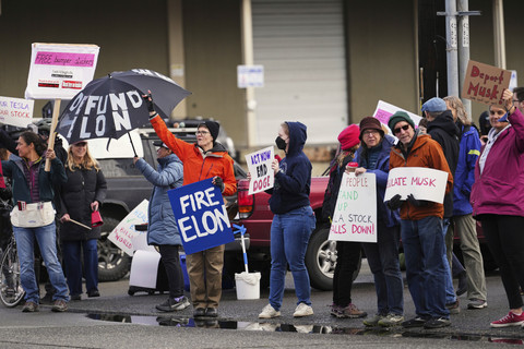 Orang-orang melambaikan tangan dan melambaikan bendera dalam sebuah protes menentang Tesla dan Elon Musk di luar ruang pamer Tesla di University District, Seattle, Sabtu (29/3/2025).  Foto: Lindsey Wasson/AP PHOTO