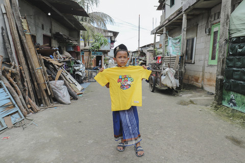Penerima Baju: Anak penerima program kumparan 'Cerita Baru untuk Bajumu' menunjukkan baju yang diterimanya di Kampung Pemulung, Duren Sawit, Jakarta Timur. Foto: Jamal Ramadhan/kumparan