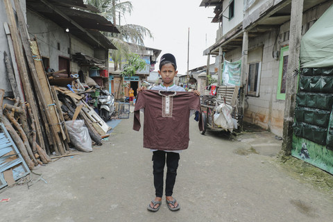 Penerima Baju: Anak penerima program kumparan 'Cerita Baru untuk Bajumu' menunjukkan baju yang diterimanya di Kampung Pemulung, Duren Sawit, Jakarta Timur. Foto: Jamal Ramadhan/kumparan