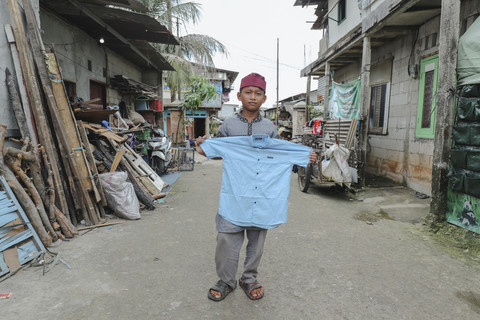 Penerima Baju: Anak penerima program kumparan 'Cerita Baru untuk Bajumu' menunjukkan baju yang diterimanya di Kampung Pemulung, Duren Sawit, Jakarta Timur. Foto: Jamal Ramadhan/kumparan