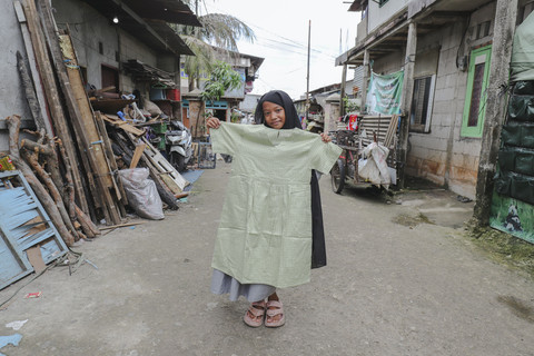 Penerima Baju: Anak penerima program kumparan 'Cerita Baru untuk Bajumu' menunjukkan baju yang diterimanya di Kampung Pemulung, Duren Sawit, Jakarta Timur. Foto: Jamal Ramadhan/kumparan