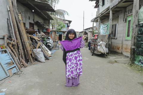Penerima Baju: Anak penerima program kumparan 'Cerita Baru untuk Bajumu' menunjukkan baju yang diterimanya di Kampung Pemulung, Duren Sawit, Jakarta Timur. Foto: Jamal Ramadhan/kumparan