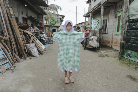 Penerima Baju: Anak penerima program kumparan 'Cerita Baru untuk Bajumu' menunjukkan baju yang diterimanya di Kampung Pemulung, Duren Sawit, Jakarta Timur. Foto: Jamal Ramadhan/kumparan