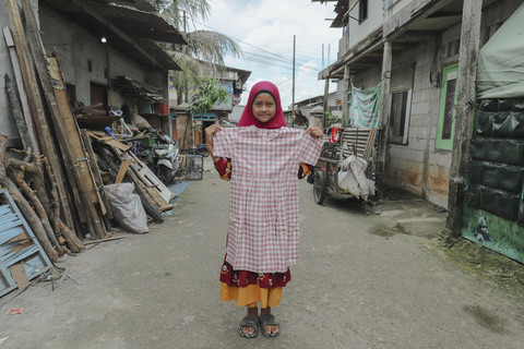 Penerima Baju: Anak penerima program kumparan 'Cerita Baru untuk Bajumu' menunjukkan baju yang diterimanya di Kampung Pemulung, Duren Sawit, Jakarta Timur. Foto: Jamal Ramadhan/kumparan