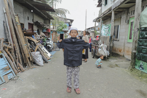 Penerima Baju: Anak penerima program kumparan 'Cerita Baru untuk Bajumu' menunjukkan baju yang diterimanya di Kampung Pemulung, Duren Sawit, Jakarta Timur. Foto: Jamal Ramadhan/kumparan