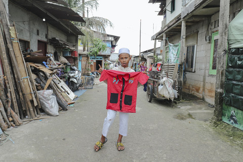 Penerima Baju: Anak penerima program kumparan 'Cerita Baru untuk Bajumu' menunjukkan baju yang diterimanya di Kampung Pemulung, Duren Sawit, Jakarta Timur. Foto: Jamal Ramadhan/kumparan