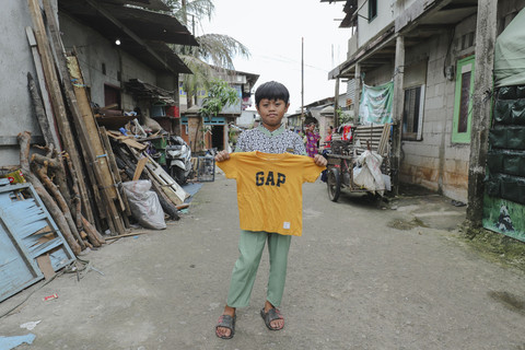 Penerima Baju: Anak penerima program kumparan 'Cerita Baru untuk Bajumu' menunjukkan baju yang diterimanya di Kampung Pemulung, Duren Sawit, Jakarta Timur. Foto: Jamal Ramadhan/kumparan
