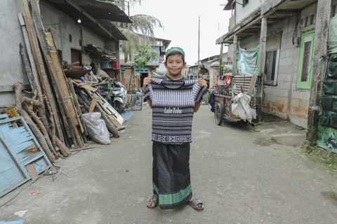 Penerima Baju: Anak penerima program kumparan 'Cerita Baru untuk Bajumu' menunjukkan baju yang diterimanya di Kampung Pemulung, Duren Sawit, Jakarta Timur. Foto: Jamal Ramadhan/kumparan