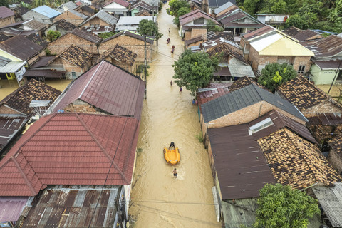 Foto udara dua anak membawa perahu karet milik BNPB saat banjir merendam kawasan permukiman di Kenali Besar, Jambi, Minggu (30/3/2025). Foto: Wahdi Septiawan/ANTARA FOTO