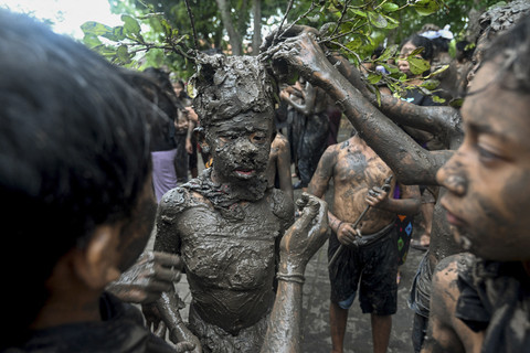 Anak laki-laki Bali menutupi diri mereka dengan lumpur selama tradisi mandi lumpur, yang dikenal sebagai Mebuug-buugan di desa Kedonganan, dekat Denpasar, pulau resor Bali, Minggu (30/3/2025). Foto: Sonny Tumbelaka/AFP