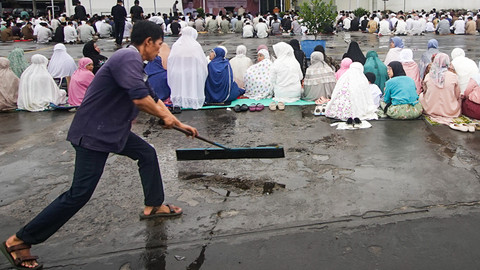 Seorang petugas kebersihan dari manajemen pusat perbelanjaan yang membersihkan area pelaksanaan salat id pasca hujan deras yang terjadi senin dini hari di Palembang, Senin (31/3) Foto: abp/urban id