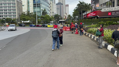 Masyarakat memanfaatkan momen sepinya Jakarta untuk berfoto di Bundaran HI, Jakarta Pusat, Selasa (1/4/2025).  Foto: Abid Raihan/kumparan
