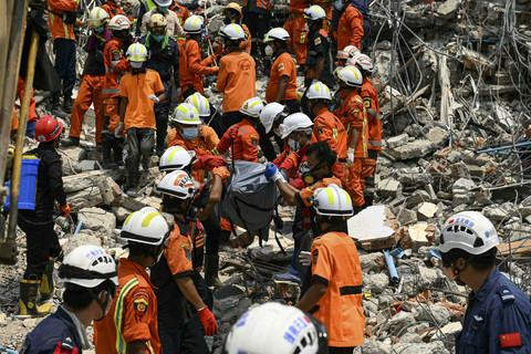 Tim penyelamat Myanmar dan Tiongkok membawa jenazah seorang korban yang terjebak di bawah reruntuhan bangunan runtuh 'pembangunan Sky Villa Condominium' di Mandalay, Myanmar, Rabu (2/4/2025). Foto: Sai Aung Main/AFP