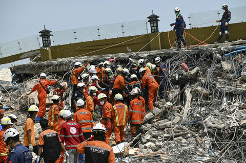 Tim penyelamat Myanmar dan Tiongkok membawa jenazah seorang korban yang terjebak di bawah reruntuhan bangunan runtuh 'pembangunan Sky Villa Condominium' di Mandalay, Myanmar, Rabu (2/4/2025). Foto: Sai Aung Main/AFP