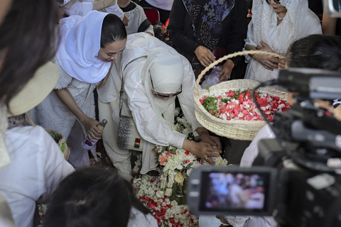 Mantan istri aktor Ray Sahetapy, Dewi Yull menaburkan bunga dan berdoa saat pemakaman di TPU Tanah Kusir, Jakarta, Jumat (4/4/2025). Foto: Jamal Ramadhan/kumparan