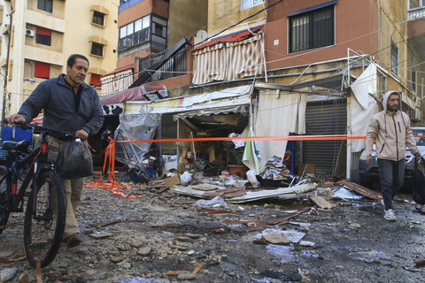 Warga setempat berjalan melewati puing-puing di depan sebuah gedung apartemen setelah serangan Israel di Sidon, Lebanon, Jumat (4/4/2025). Foto: Mahmoud Zayyat/AFP