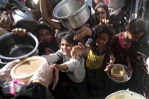 Anak-anak Palestina menerima makanan yang telah dimasak dari dapur umum di Beit Lahia, Jalur Gaza Selatan, Kamis (3/4/2025). Foto: Mahmoud Issa/REUTERS