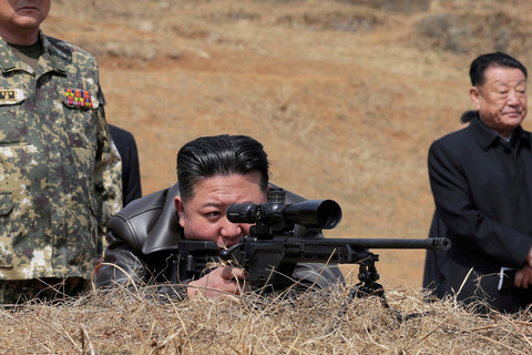 Pemimpin Korea Utara Kim Jong-un mencoba menggunakan senjata saat mengunjungi pangkalan pelatihan militer di Korea Utara, Jumat (4/7/2025). Foto: KCNA/via REUTERS