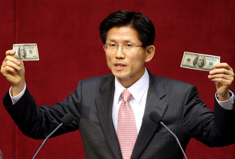 Anggota parlemen dari partai oposisi utama Partai Nasional Besar, Kim Moon-Soo menunjukkan uang kertas yang diklaim dibuat oleh Korea Utara di Majelis Nasional di Seoul, 23 Februari 2006. Foto: AFP/KIM KYUNG-JE