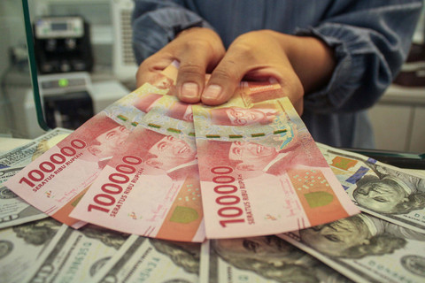 Petugas menunjukan uang pecahan dolar AS dan rupiah di gerai penukaran mata uang asing, Jakarta, Selasa (8/4/2025). Foto: ANTARA FOTO/Fathul Habib Sholeh
