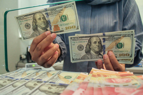 Petugas menunjukan uang pecahan dolar AS dan rupiah di gerai penukaran mata uang asing, Jakarta, Selasa (8/4/2025). Foto: ANTARA FOTO/Fathul Habib Sholeh