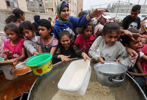 Warga Palestina berkumpul untuk menerima makanan yang dimasak oleh dapur amal, di Nuseirat, Jalur Gaza bagian tengah, 8 April 2025. Foto: REUTERS/Ramadan Abed