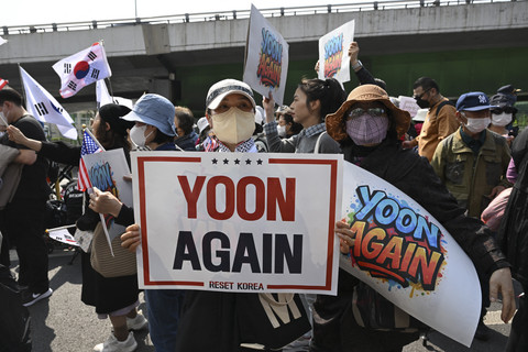 Seorang warga membentangkan poster saat menunggu keluarnya mantan presiden Korea Selatan Yoon Suk-yeol dari rumah dinas di Seoul, Korea Selatan, Jumat (11/4/2025). Foto: Jung Yeon-je/AFP