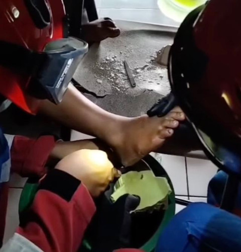 Saat Damkar Jakarta Timur melepaskan sandal yang nempel di kaki bocah. Dok: @damkarjakartatimur