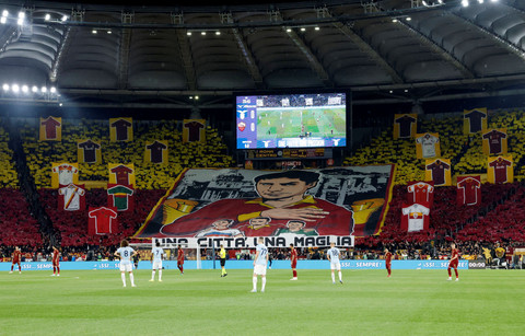 Suporter bentangkan banner wajah Agostino Di Bartolomei dan jersey saat SS Lazio vs AS Roma dalam laga pekan ke-32 Liga Italia 2024/25 di Stadio Olimpico, Senin (13/4) dini hari WIB. Foto: REUTERS/Remo Casilli