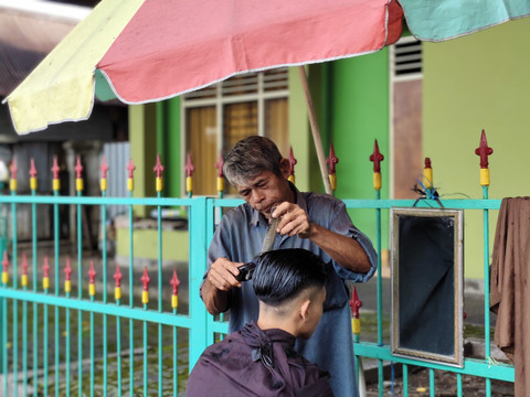 Udin tukang cukur rambut di Alun-alun Utara Yogyakarta, Rabu (16/4/2025). Foto: Arfiansyah Panji Purnandaru/kumparan