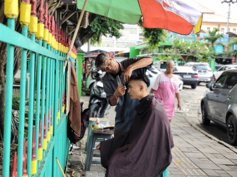 Udin tukang cukur rambut di Alun-alun Utara Yogyakarta, Rabu (16/4/2025). Foto: Arfiansyah Panji Purnandaru/kumparan