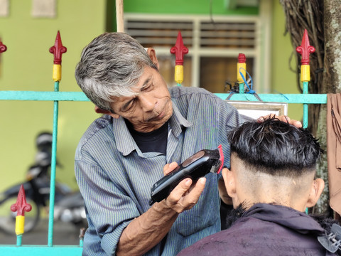 Udin tukang cukur rambut di Alun-alun Utara Yogyakarta, Rabu (16/4/2025). Foto: Arfiansyah Panji Purnandaru/kumparan