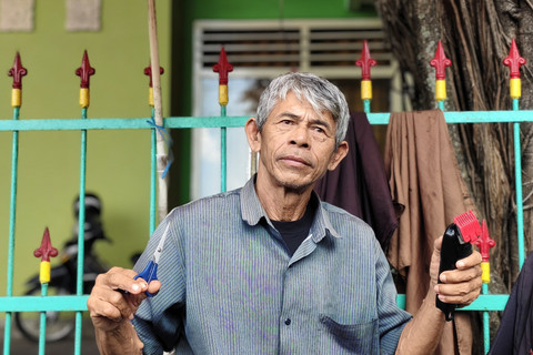 Udin tukang cukur rambut di Alun-alun Utara Yogyakarta, Rabu (16/4/2025). Foto: Arfiansyah Panji Purnandaru/kumparan