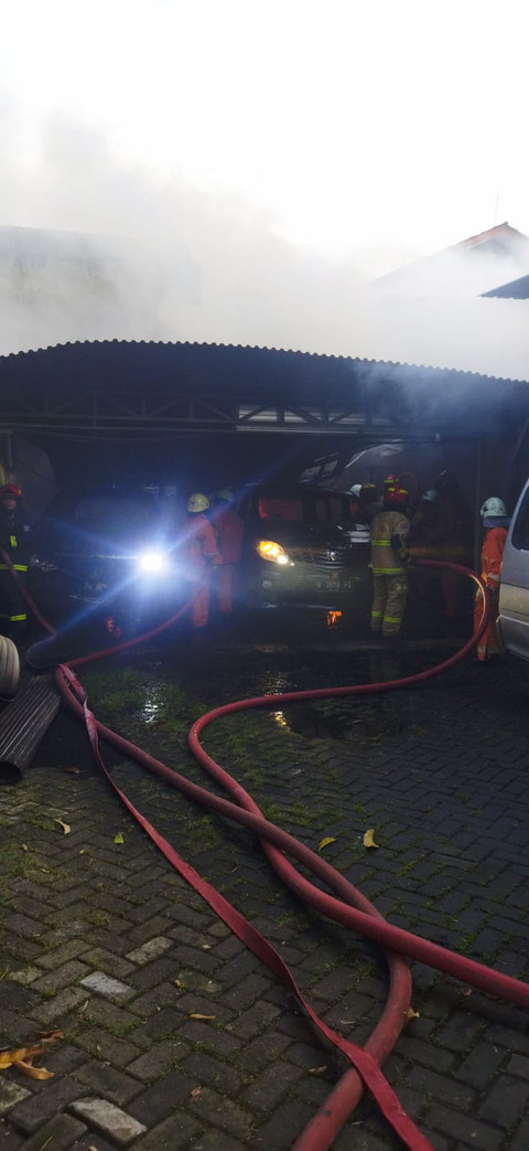 Pemadam kebakaran berusaha memadamkan api yang membakar garasi mobil rumah eks Anggota DPR Azam Azman di Surabaya, Sabtu (19/4). Foto: dok. Damkar Surabaya