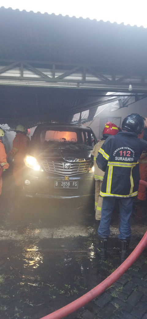 Pemadam kebakaran berusaha memadamkan api yang membakar garasi mobil rumah eks Anggota DPR Azam Azman di Surabaya, Sabtu (19/4). Foto: dok. Damkar Surabaya