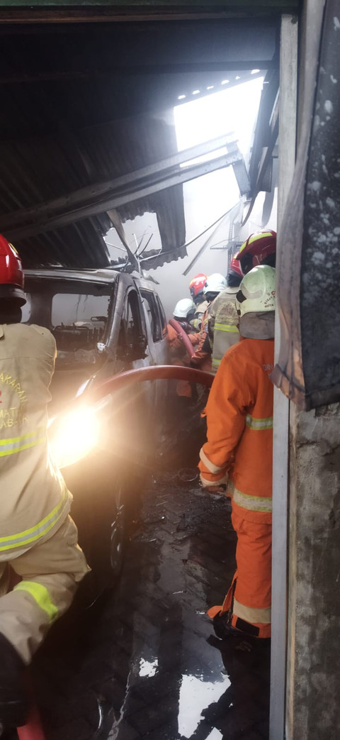 Pemadam kebakaran berusaha memadamkan api yang membakar garasi mobil rumah eks Anggota DPR Azam Azman di Surabaya, Sabtu (19/4). Foto: dok. Damkar Surabaya