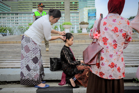 Perempuan yang mengenakan kebaya menata rambutnya saat memperingati Hari Kartini di car free day (CFD) Kawasan Bundaran HI, Jakarta, pada Minggu (20/4/2025). Foto: Jamal Ramadhan/kumparan