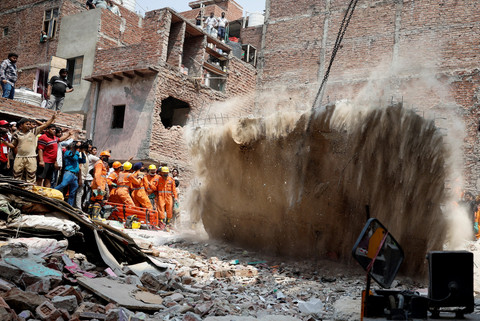 Petugas tanggap memindahkan lempengan bangunan runtuh di New Delhi, India, Sabtu (19/4/2025). Foto: Adnan Abidi/REUTERS