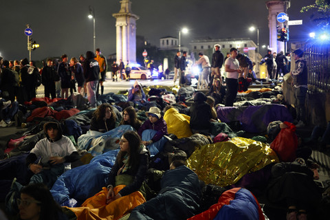 Sejumlah warga berisitrahat saat menunggu Misa Pemakaman Paus Fransiskus di kawasan Roma, Italia, Sabtu (26/4/2025) dini hari. Foto: Henry Nicholls/AFP
