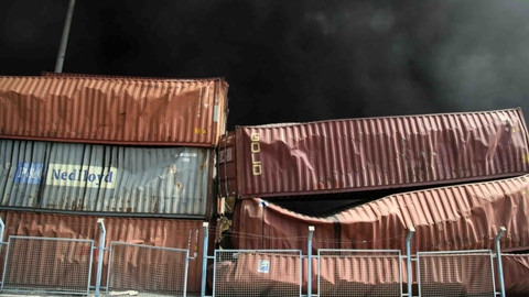 Asap hitam mengepul di belakang kontainer yang rusak menyusul ledakan di dermaga pelabuhan Shahid Rajaee. Foto: MOHAMMAD RASOLE MORADI / IRNA / AFP