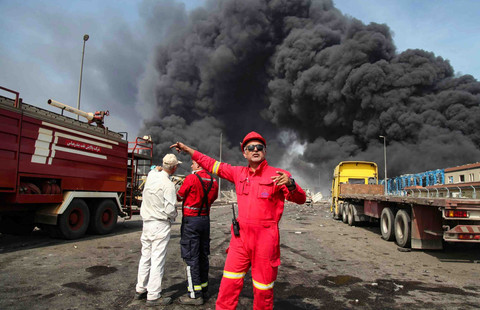 Asap hitam pekat mengepul saat tim penyelamat tiba di dekat sumber ledakan di dermaga pelabuhan Shahid Rajaee Foto: MOHAMMAD RASOLE MORADI / IRNA / AFP