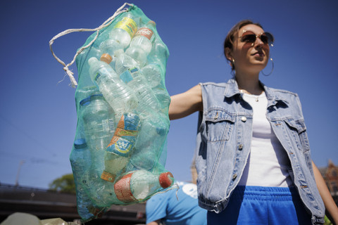 Seorang wanita memegang tas penuh dengan botol plastik yang diambil dari kanal Amsterdam, Belanda, Minggu (27/4/2025). Foto: Simon Wohlfahrt/AFP