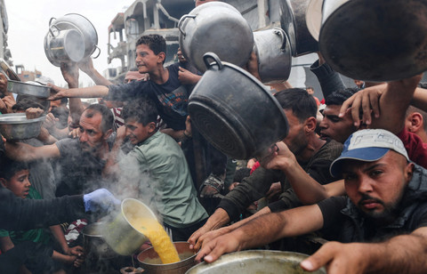 Warga Palestina berkumpul untuk menerima makanan yang dimasak oleh dapur amal di Beit Lahia, Jalur Gaza utara, Kamis (24/4/2025). Foto: Mahmoud Issa/REUTERS
