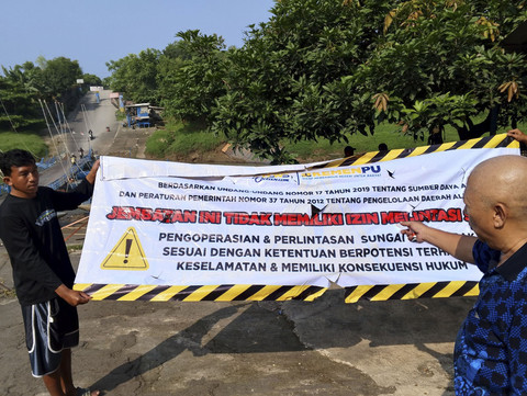 Endang Junaedi memperlihatkan spanduk peringatan yang dipasang BBWS Citarum di jembatan perahu miliknya. Foto: Dok. Istimewa